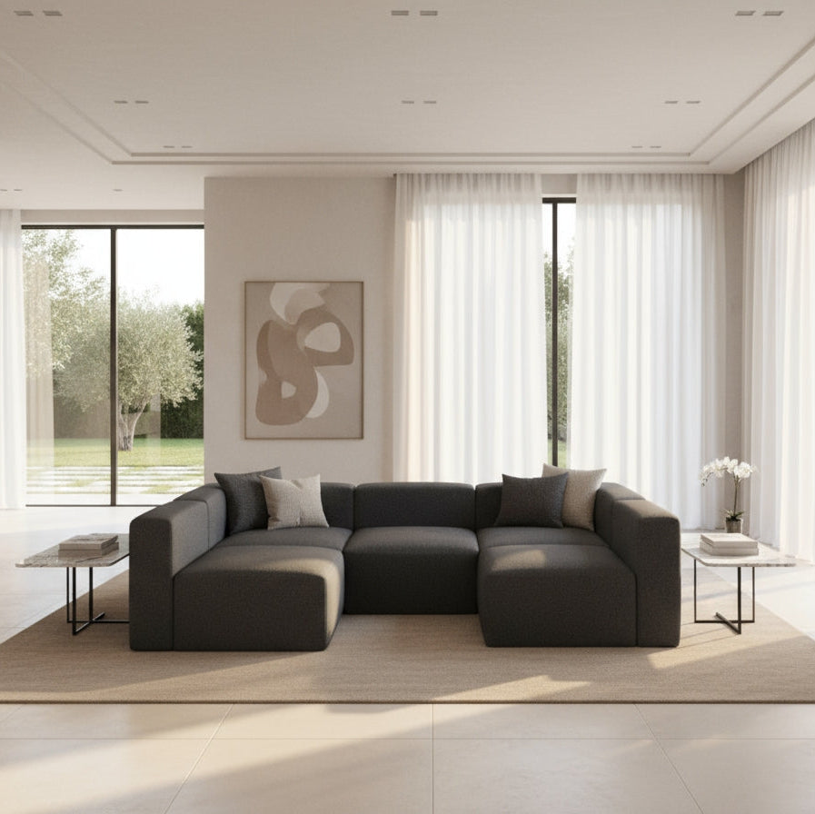 Modern living room with a large gray sectional sofa, abstract painting, and large windows.